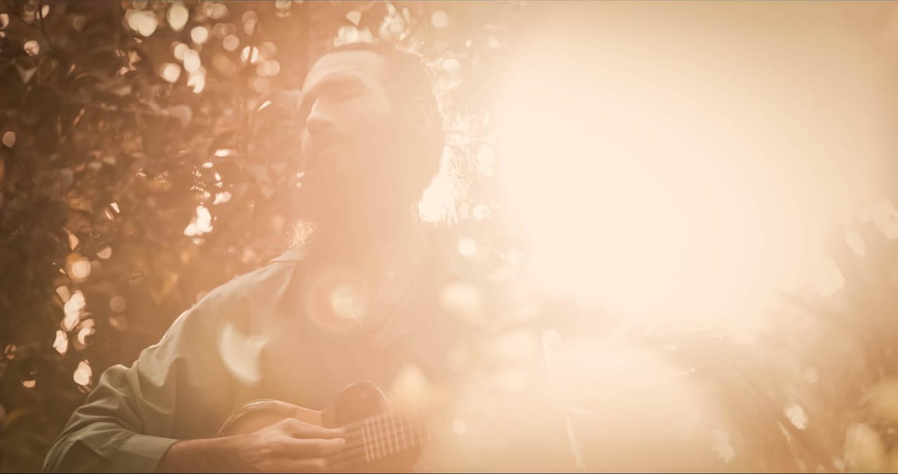 Michael playing charango outdoors in low golden sunlight