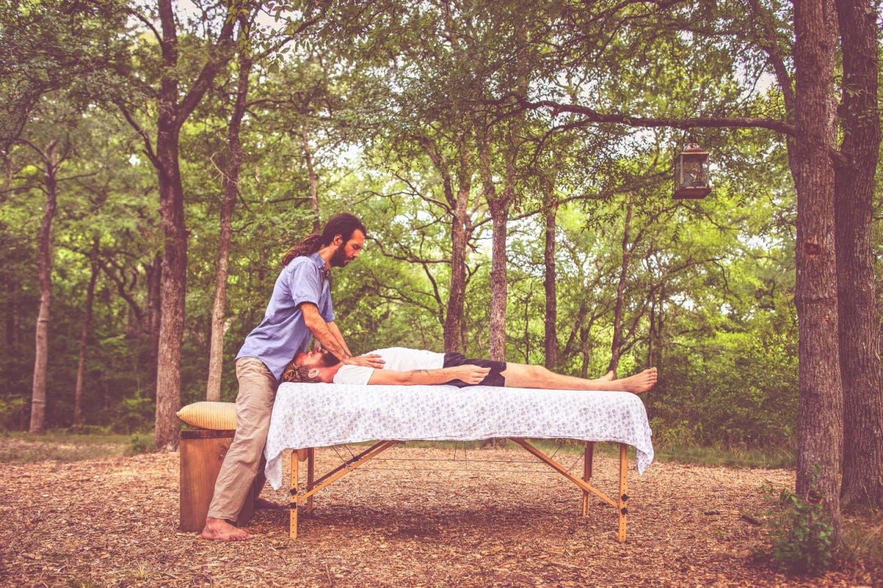 Michael working with a client on a table in an open clearing among oak trees